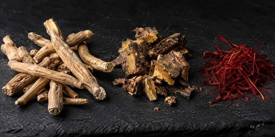 Korzeń ashwagandhy, różeniec górski i nitki szafranu na ciemnym tle