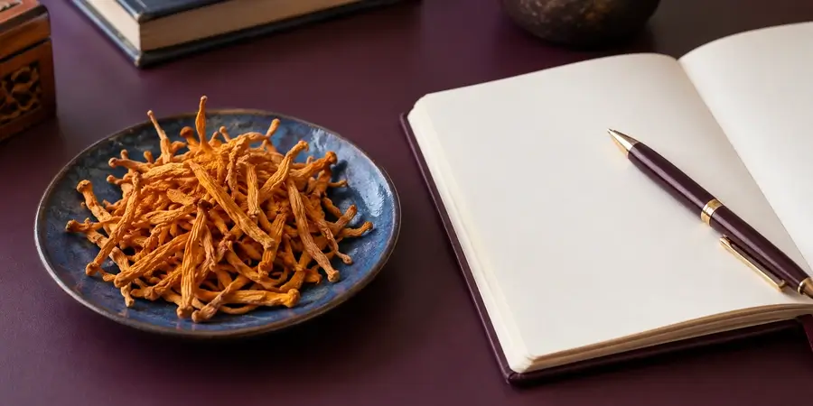 Suszony cordyceps na talerzyku obok otwartego notatnika i pióra